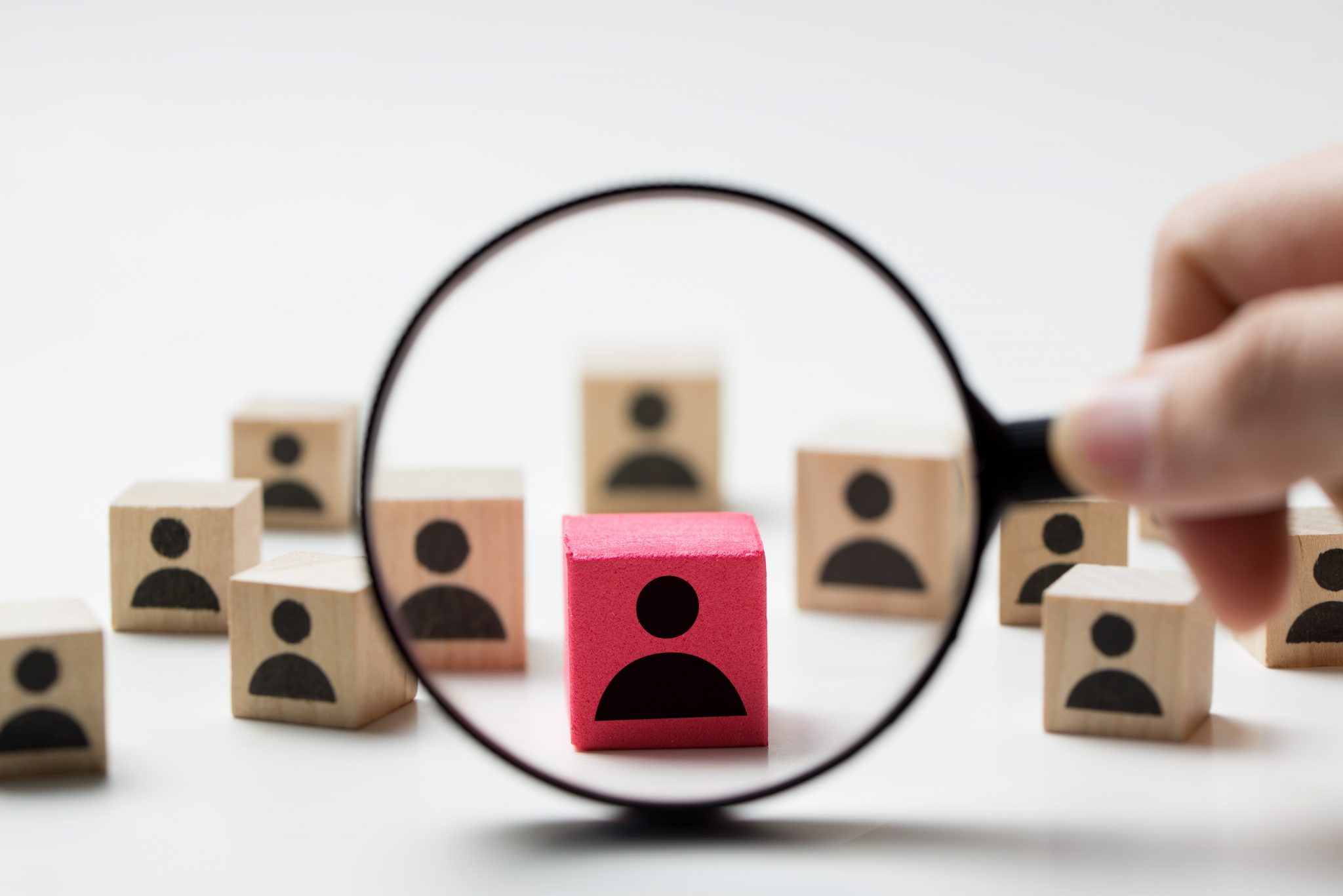 magnifying glass with wooden blocks representing recruiting 