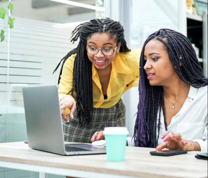 employees discuss coaching styles whilst looking at a laptop in an office environment 