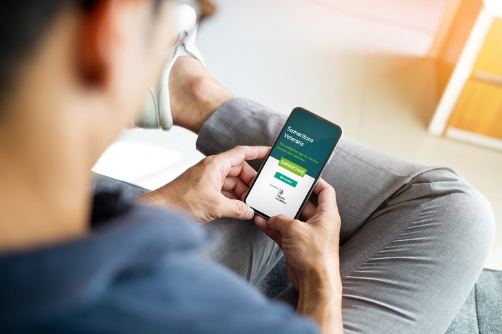 Man holding phone using the Samaritans veterans app mobile learning experience 